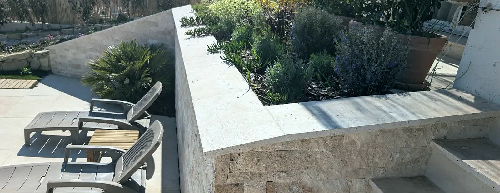 Terrasse et jardinière en travertin autour d'une piscine