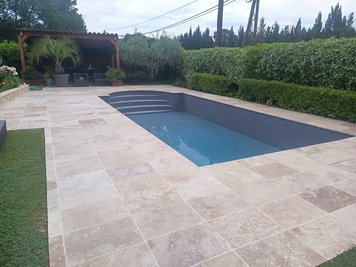 Piscine terminée entourée d'une plage en travertin